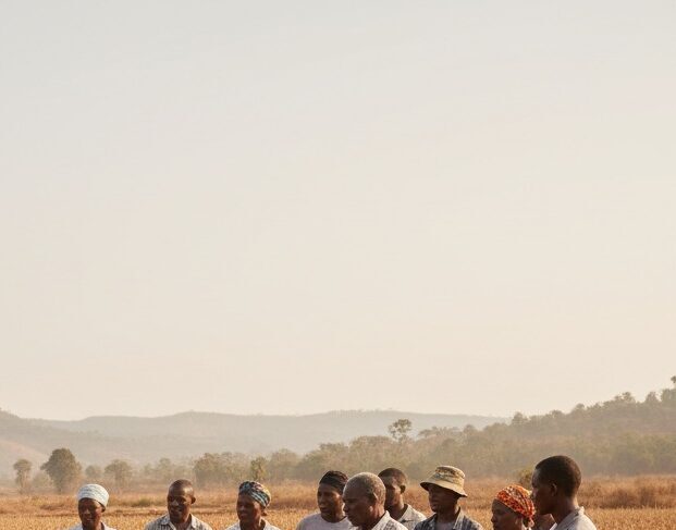 Un groupe de personnes se tient dans un champ aride et sec, tenant une banderole informant sur la rareté des pluies au Sud-Kivu.